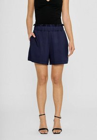 Marineblaue Shorts mit einem rüschigen, elastischen Bund, seitlichen Taschen und lockerer Passform. Glatte Textur und Länge bis zur Mitte des Oberschenkels.