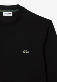 Felpa nera in misto cotone, con logo coccodrillo ricamato in verde e bianco sul lato sinistro. Vestibilità classica, scollo a coste.