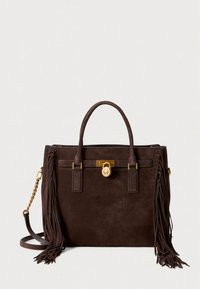 Καφέ τσάντα από σουέντ με δύο χειρολαβές στο πάνω μέρος, αποσπώμενο ιμάντα ώμου, μεταλλικά στοιχεία σε χρυσή απόχρωση και διακοσμητικές φουντίτσες.