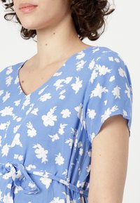 Abito floreale blu con motivi a fiori bianchi, maniche corte, scollo a V e fascia in vita. Realizzato in tessuto leggero, presenta una vestibilità comoda.