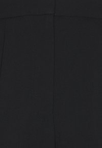 Zblízka černá texturovaná tkanina ukazující detailní šití a švy.