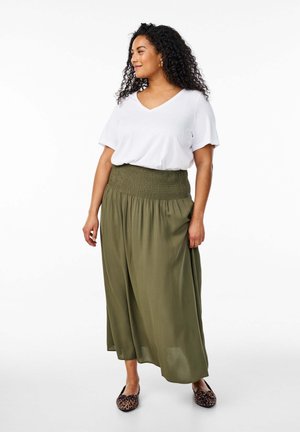 T-shirt blanc à col en V associé à un pantalon fluide taille haute vert olive avec une taille smockée, complété par des ballerines à imprimé animal.