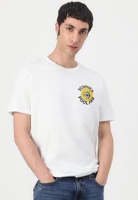 T-shirt en coton blanc avec un col rond et des manches courtes, présentant un graphique de tournesol jaune et le texte "SUNNIE'S POOLBAR" sur la poitrine.
