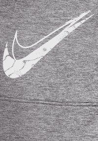 Grå atletisk stof har et stort, slidte hvidt Nike swoosh-logo med synlig tekstur og sømdetaljer.