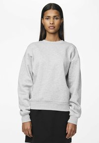 Sudadera gris de corte relajado, con mangas largas, cuello redondo y puños acanalados; combinada con una falda negra. Textura de tela suave, diseño casual.