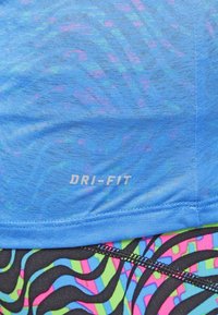 Light blue Dri-Fit fabric with a mottled pattern. Below, patterned black leggings feature bright pink, green, and blue wave designs.