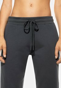 Grijze sweatpants met een trekkoord in de taille, gemaakt van zachte stof. Heeft een gladde textuur en een ontspannen pasvorm met twee zijzakken.