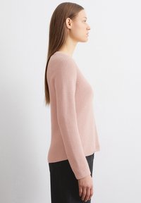 Helles rosa geripptes Sweatshirt mit langen Ärmeln, runder Ausschnitt und taillierter Silhouette. Hergestellt aus einem strukturierten Strickstoff.