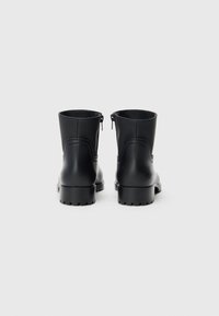 Black leather ankle boots with a smooth finish, rounded toe, chunky heel, and zippers at the back for easy access.