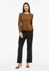 Pruun soonikkoeseme pika varrukaga, mille juurde on kombineeritud mustad laiade säärtega püksid. Täiendatud pruunide terava ninaga kontsadega.