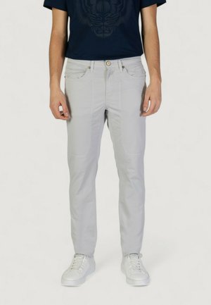 Pantaloni grigi chiari con una texture liscia, dotati di tasche inserite, dettagli di cucitura discreti e una vestibilità slim, abbinati a sneakers bianche.