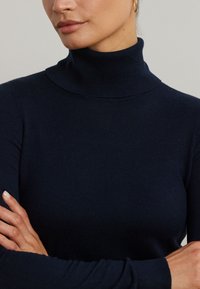 Navyblauer Pullover mit Mock-Neck aus weichem Strickmaterial, taillierte Passform, mit langen Ärmeln und dezent geripptem Detail am Kragen.