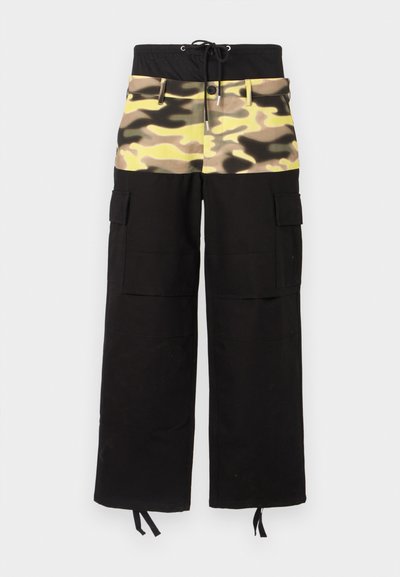 Cargo hlače s črnim materialom in zgornjim delom v kamuflažnem vzorcu v odtenkih rumene, zelene in rjave; vključujejo nastavljiv pas.