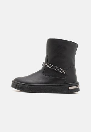 Schwarzer Mid-Calf-Stiefel mit flacher Gummisohle, dekorativem, mit Metallnieten besetztem Riemen und metallischem Akzent an der Ferse.