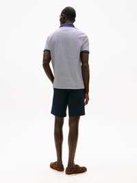 Marineblå og hvite stripete polo skjorte med krage, kombinert med marineblå shorts og brune båt-sko. Stoffet er glatt med en klassisk passform.
