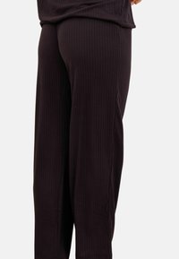 Pantalons en tricot côtelé noirs avec une coupe décontractée, présentant une texture douce et une taille élastique pour plus de confort.