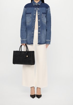 Czarna pleciona torebka o prostokątnym kształcie, gładkiej fakturze i dwóch uchwytach. W połączeniu z dżinsową koszulą i białymi spodniami o szerokich nogawkach.