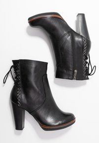 Stivali alla caviglia neri con tacco realizzati in materiale sintetico testurizzato. Presentano una cerniera laterale, un dettaglio con lacci sul retro e un accento in legno sulla suola.