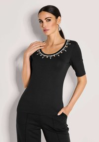 Zwart shirt met korte mouwen en een ronde hals, met een decoratieve halslijn van heldere en metalen versieringen. Soepele stof.