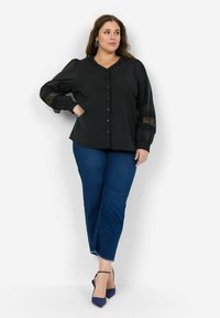 Svart knapp-up blus med puffärmar, spetsdetaljer vid ärmslut, kombinerad med blå jeans och marinblå klackar, med en avslappnad passform och enfärgade nyanser.