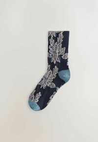 En enkelt navy sok med lyseblå hæl og tå, der har beige og lyseblå detaljerede blomster mønstre.
