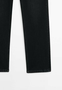 Jean en denim noir avec une coupe droite, présentant des coutures classiques et un ourlet net. La texture semble lisse et résistante.