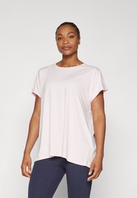 Light pink athletic top with short sleeves, round neckline, and a loose fit. Made from smooth fabric; features a side split detail.