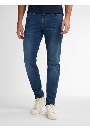 Donkerblauwe denim jeans met een slim fit, voorzien van vijf zakken en subtiele vervaging. Gepaard met witte sneakers voor een casual look.