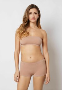 Lysebrun bandeau-top og hipster-shorts lavet af glat, strækbart stof. Simpelt design uden mønstre, med bløde kanter og en tætsiddende pasform.