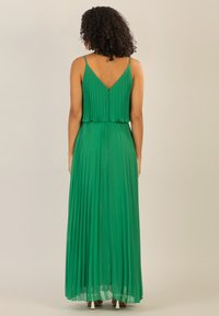 Grünes plissiertes Maxikleid mit Spaghettiträgern, V-Ausschnitt, Lagen-Design und einem verdeckten Reißverschluss; fließender Stoff mit einer weichen Textur.
