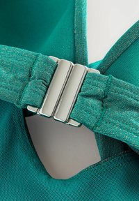 Teal sportbeha met een metallic gouden glans, voorzien van een brede band en verstelbare metallic sluiting voor een veilige pasvorm. Glad, gestructureerd materiaal.