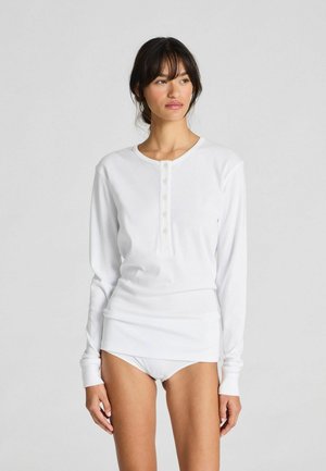 Witte lange mouwen shirt met ronde hals, knoopsluiting aan de voorkant en zachte stof, gecombineerd met bijpassend wit ondergoed.