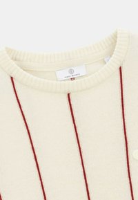 Pull crème avec des rayures rouges verticales, col côtelé et une petite étiquette logo. Texture douce et design classique de col rond.