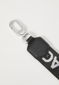 Black fabric strap featuring a textured leather accent, silver metal clasp, and white printed letters.
