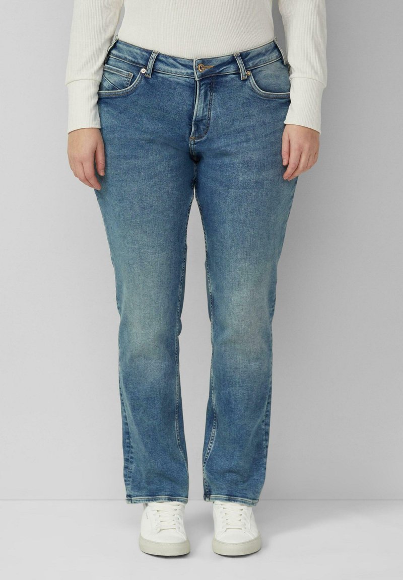 Jasnoniebieskie dżinsy z prostą nogawką, wyposażone w pięć kieszeni, delikatne przetarcia oraz zapięcie na guzik, zestawione z białymi trampkami.