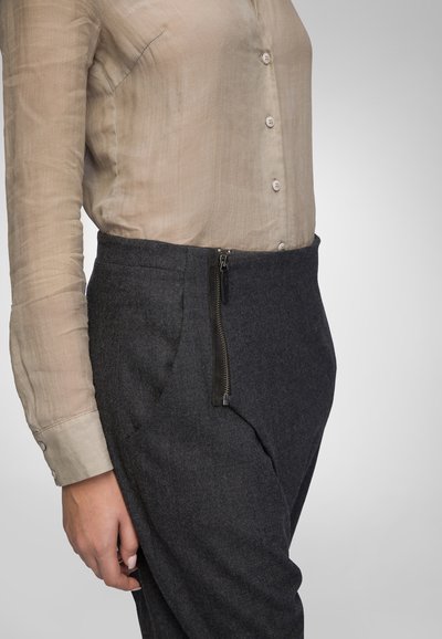 Beige semi-sheer button-up blouse paired with dark gray tailored trousers featuring a visible side zipper and smooth texture.