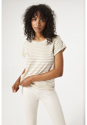 Haut à manches courtes rayé en crème avec des rayures beiges. Tissu doux, col rond et manches à revers. Associé à un pantalon de couleur claire.