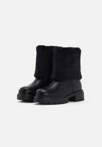 Cizme negre până la gleznă cu manșetă din blană artificială, superior din piele netedă, talpă chunky și model texturat pentru un grip suplimentar.