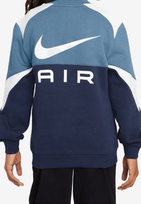 Bluza Nike w niebiesko-granatowej kolorystyce, z dużym białym logo "AIR" oraz charakterystycznym swooshem Nike na plecach. Miękka tekstura.