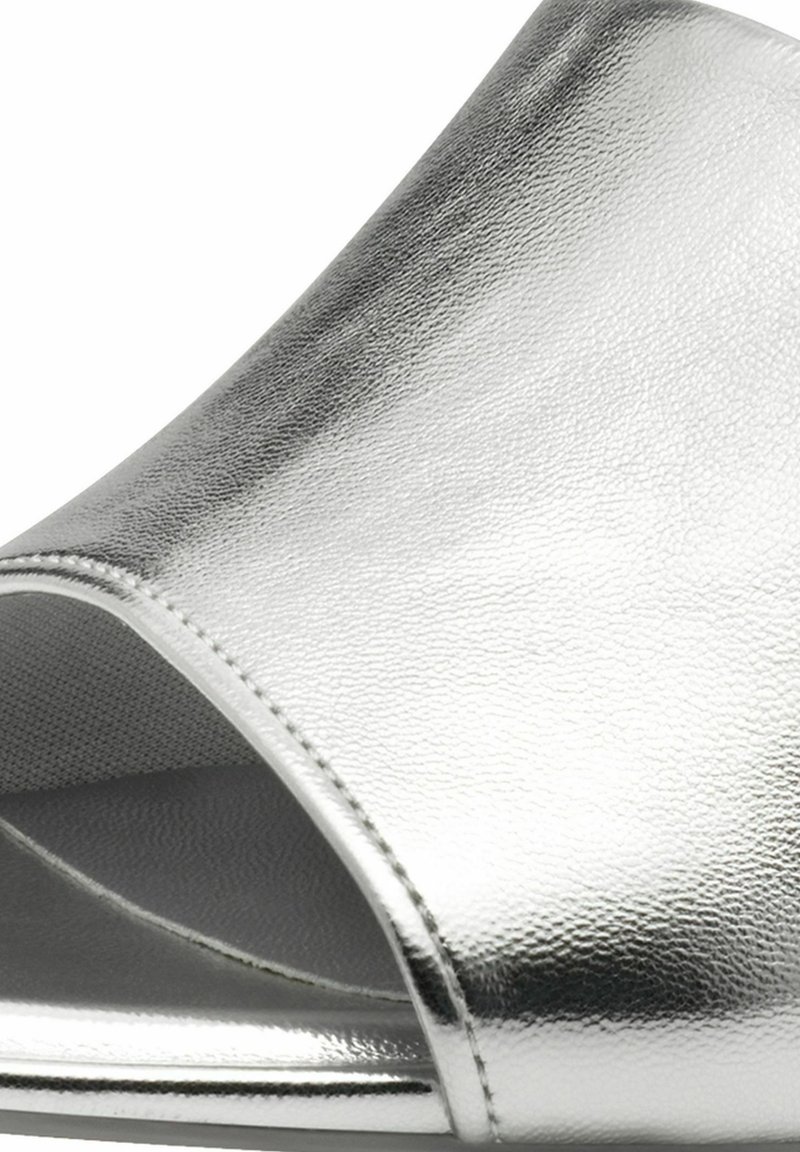 Silberne Riemchensandale mit offenem Zehenbereich, einer glatten, metallischen Oberfläche und subtiler Textur. Verfügt über einen geschwungenen Schaft und eine flache Sohle für einfaches Tragen.