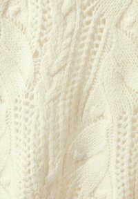 Maglione a trecce di colore crema, con motivi testurizzati, filato spesso e sezioni a lavorazione aperta che creano un aspetto stratificato. Finitura morbida.