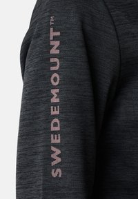 Rękaw ciemnoszarej melanżowej bluzy z nadrukiem słowa "SWEDEMOUNT" w różowych blokowych literach, umieszczonymi pionowo wzdłuż ramienia.