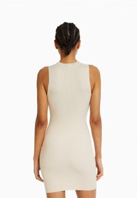 Robe moulante en tricot côtelé de couleur beige clair, sans manches, avec un col rond, une forme ajustée et une longueur mi-genou.