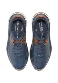 Marinblå sneakers med en texturerad ovandel, perforerade detaljer, bruna läderaccenter och en vadderad sula för komfort.