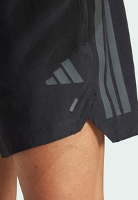 Pantalones cortos deportivos negros confeccionados en tejido texturizado, con acentos en gris de 3 rayas y logotipo, y un dobladillo ventilado para una mayor movilidad.
