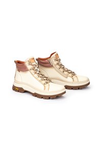 Botas de senderismo blancas y marrones que cuentan con un collar acolchado, ojales metálicos y una suela marrón resistente con un patrón texturizado.