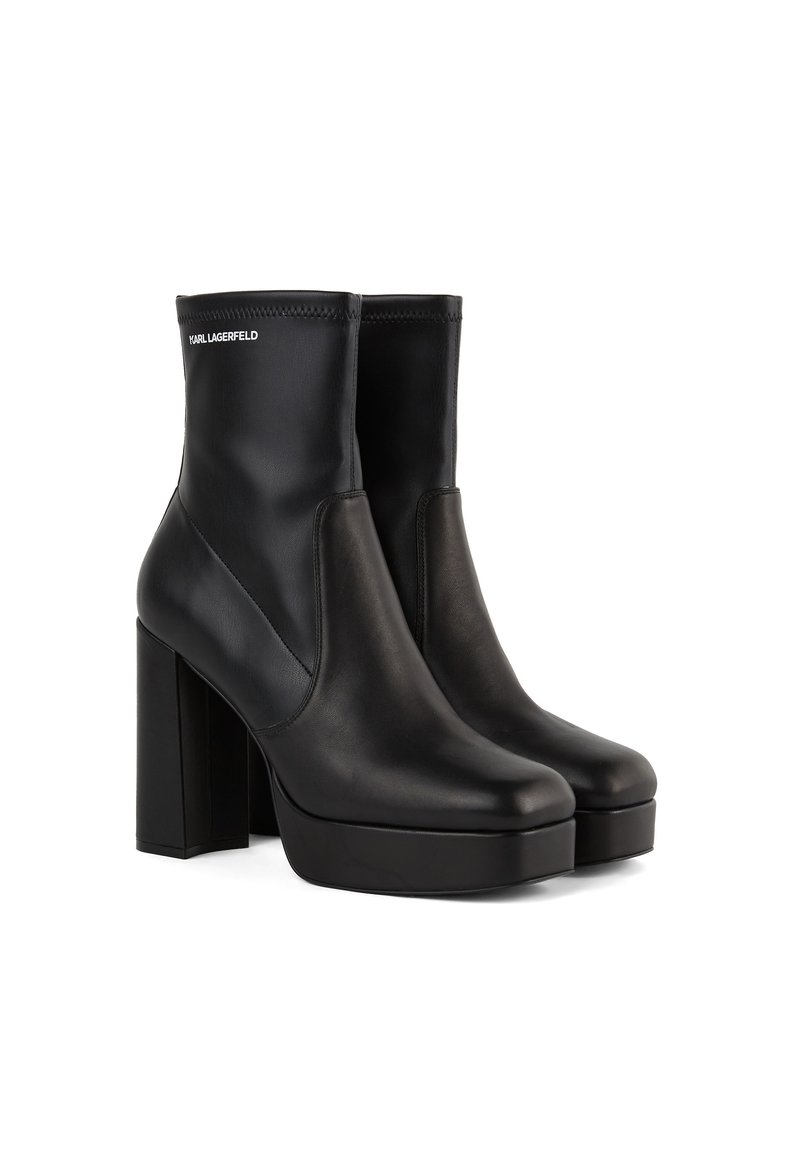 Zwarte enkellaarzen van glad leer met een hoge blokhak, elastische zijkanten en een logo-detail aan de bovenkant. Stijlvol, minimalistisch ontwerp.