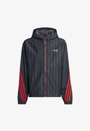 Chaqueta cortavientos negra con capucha, con franjas verticales rojas en las mangas, cremallera frontal y logo de la marca. Hecha de material ligero.