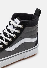 Sneakers alte in suede grigio e tessuto nero, con una striscia ondulata bianca, occhielli in metallo e suola in gomma con fondo in gomma.