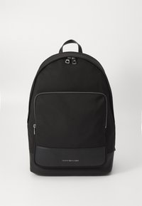 Zaino in nylon nero con parte superiore arrotondata, una tasca frontale con zip e un pannello inferiore in pelle. Presenta zip e dettagli del logo in tonalità argento.